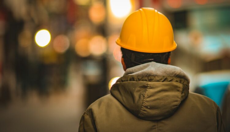 person in yellow hard hat and brown jacket